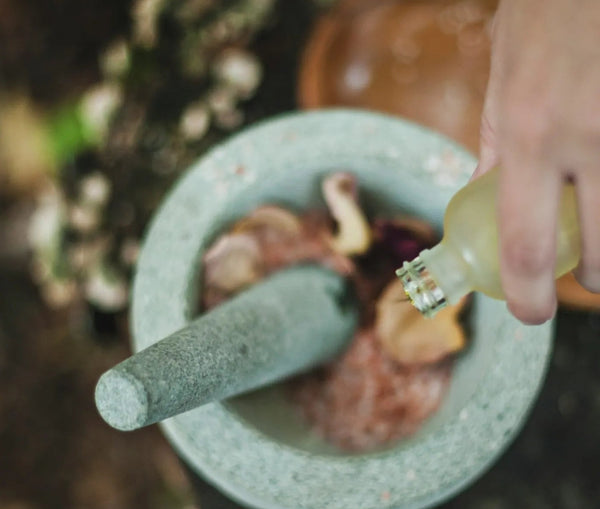 Mortar and pestle with herbs on a natural background