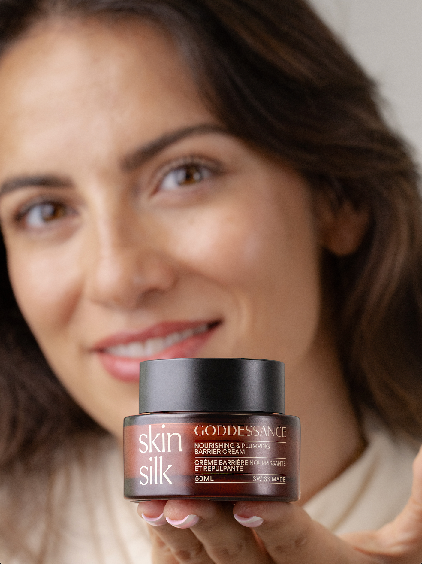 Smiling woman holding a Skin Silk barrier cream jar